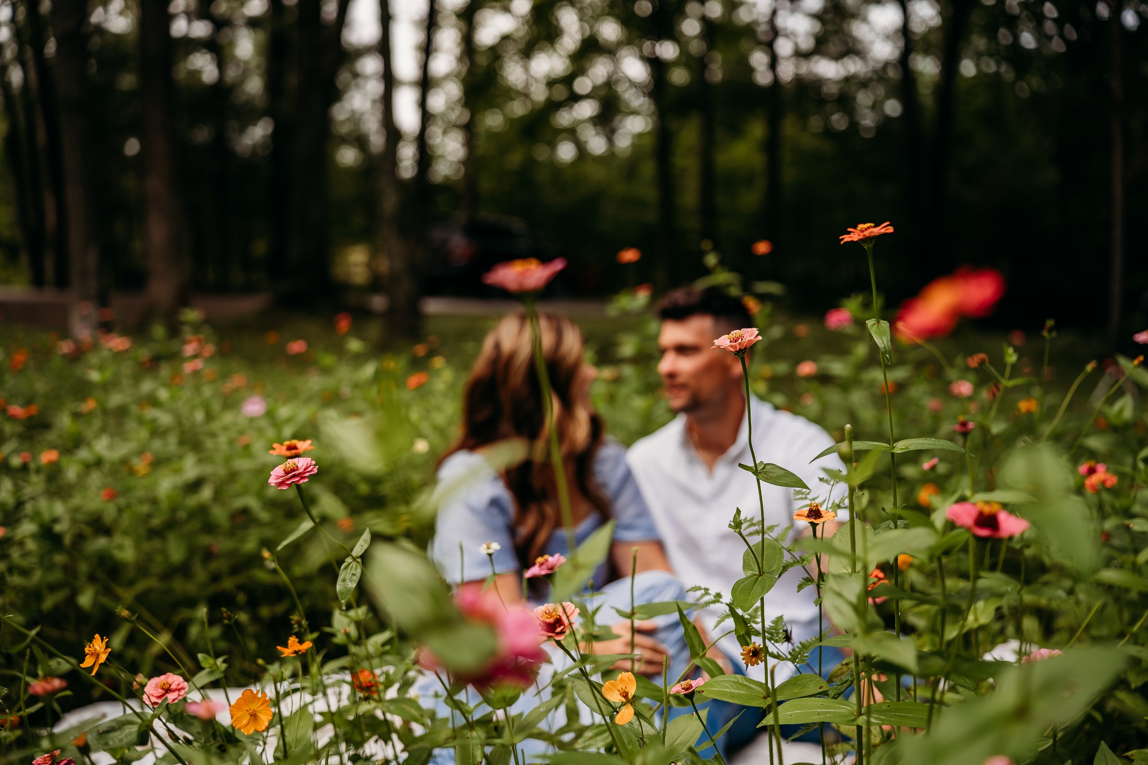 Couple sitting together among the zinnias in the wildflower field