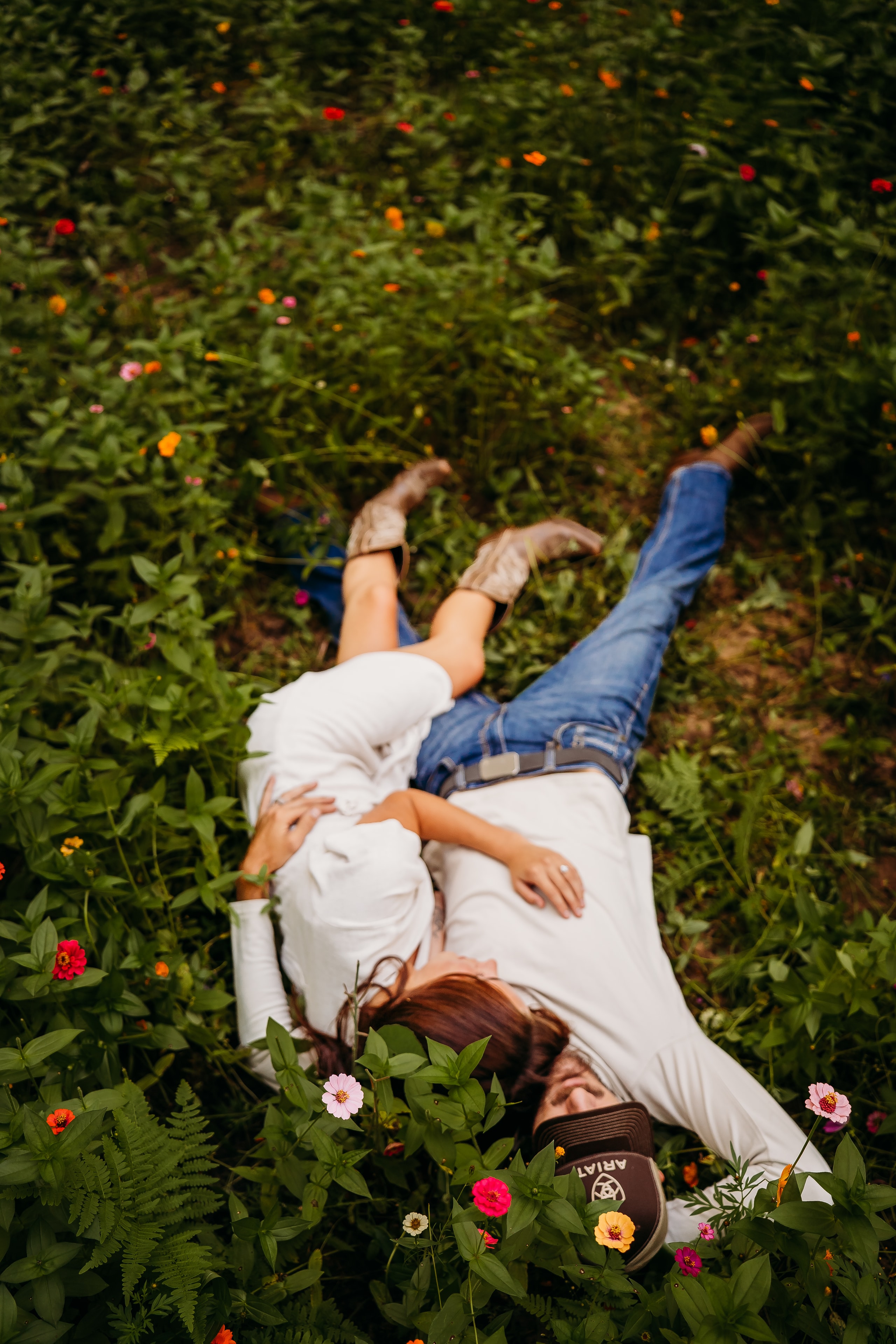 Couple lying back-to-back among the wildflowers, seen from above