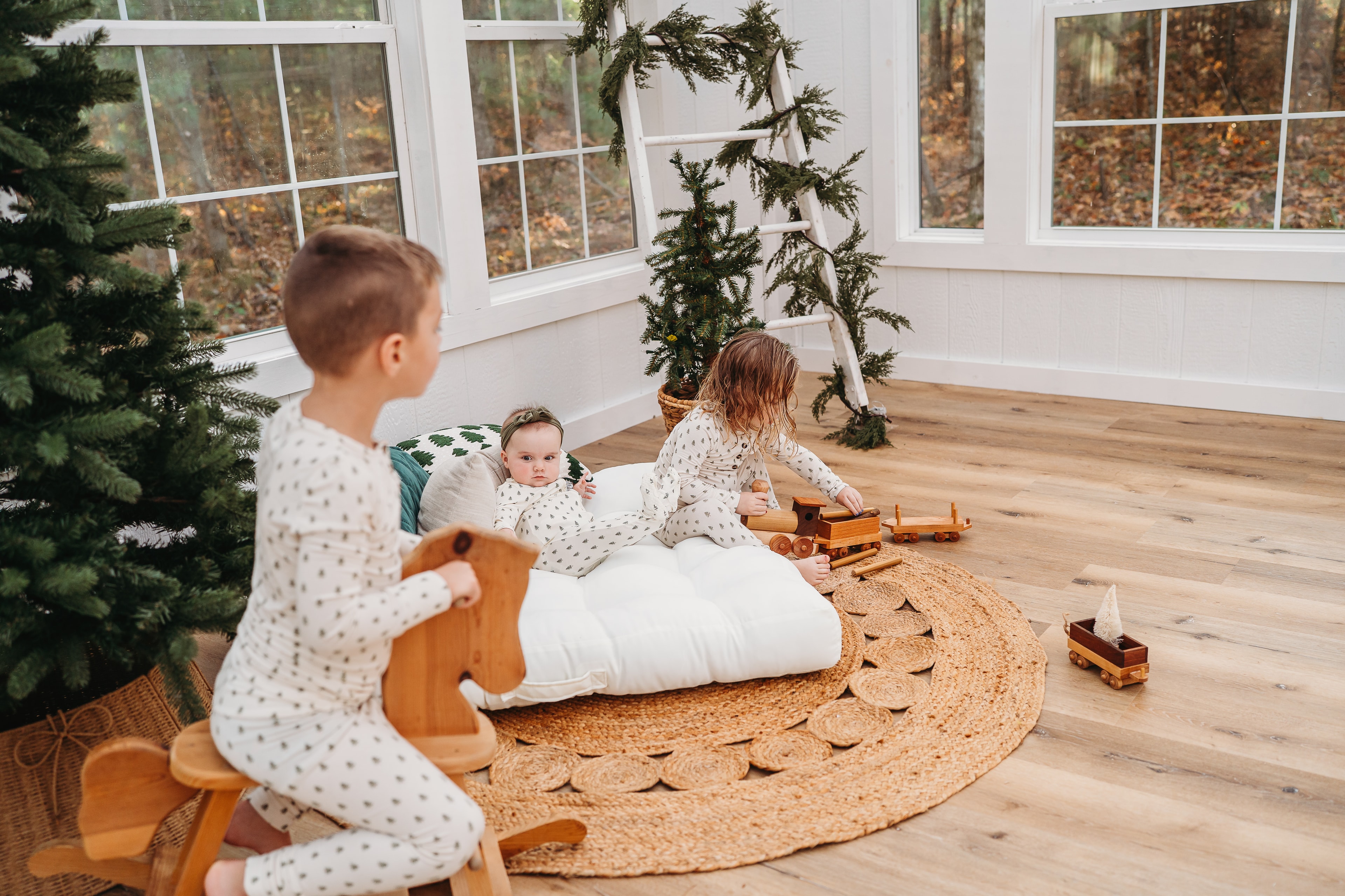 Children in pajamas playing with wooden toys in the studio styled for Christmas